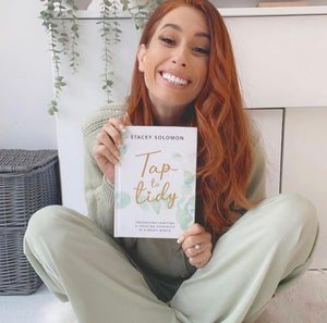 Stacey Solomon is holding a book and smiling at the camera. 
